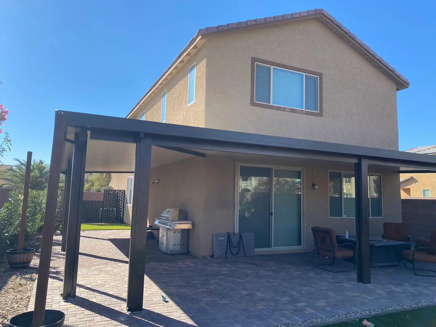 Backyard with an outdoor kitchen, pergola, pavers and artificial turf