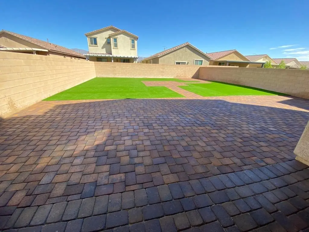 Large paver patio meeting artificial turf in a Las Vegas backyard
