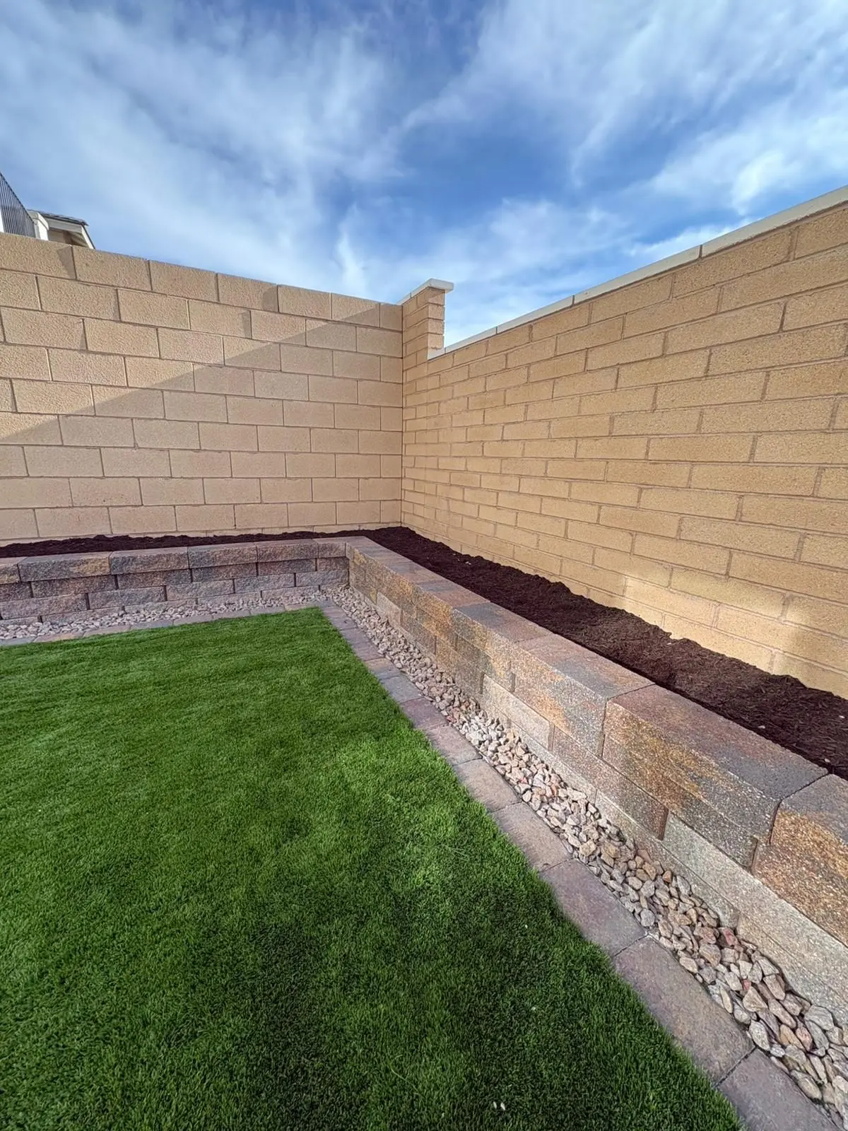 Raised block planter along a backyard wall