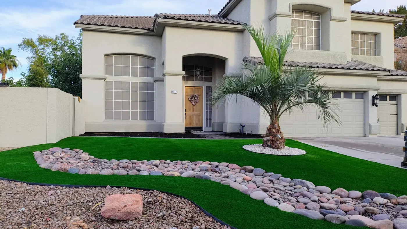Front yard with river rock, a palm tree and turf